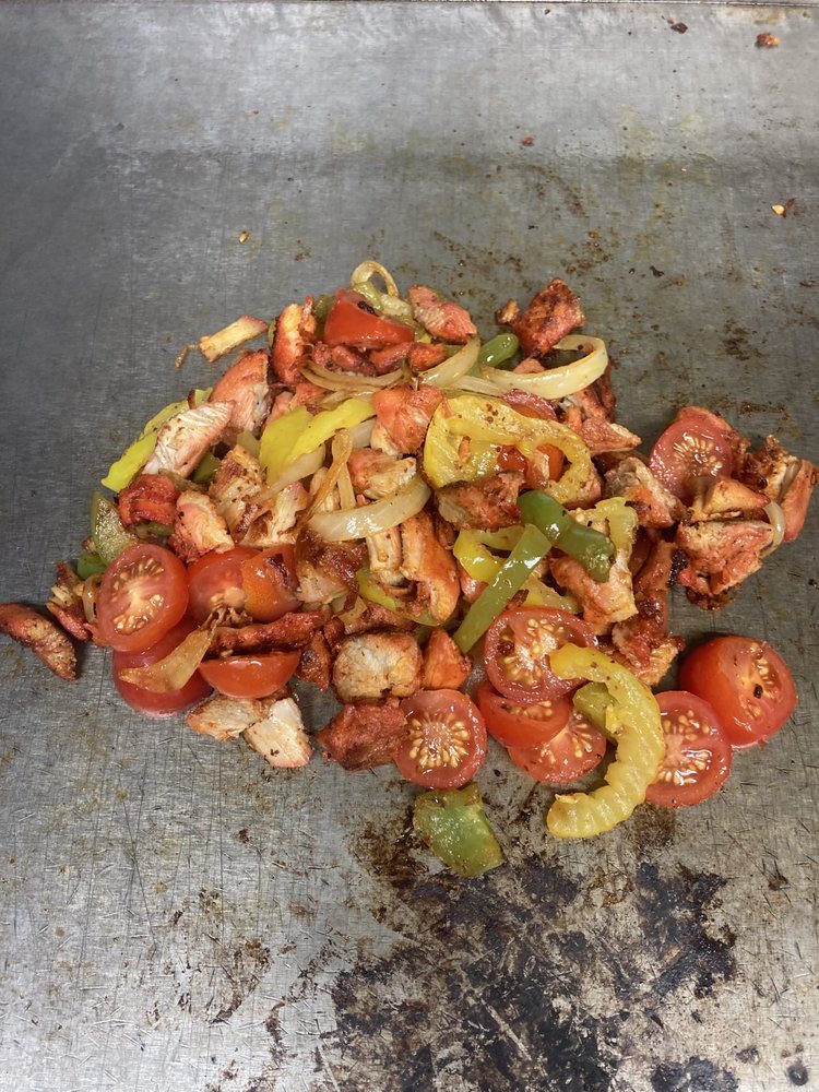 Chicken searing on the flat top with peppers and tomato